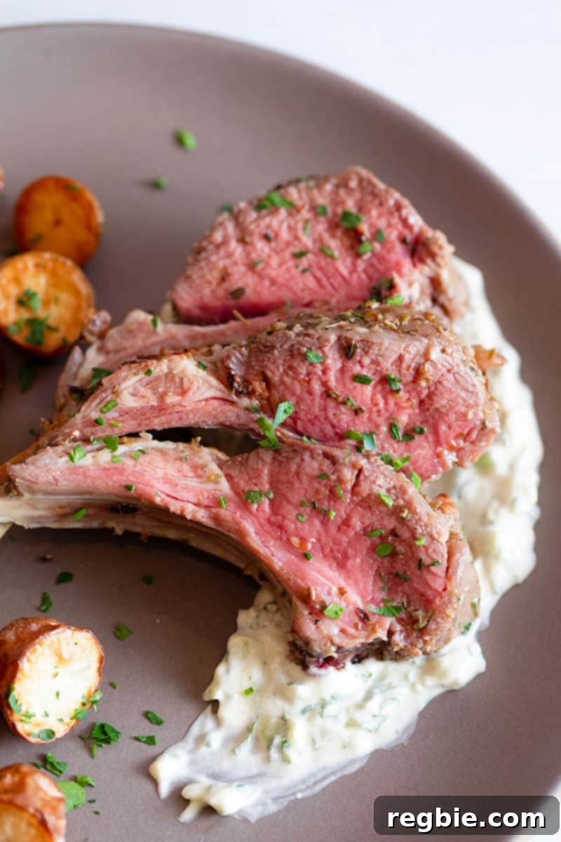 An overhead shot of a rustic brown platter elegantly arranged with three succulent lamb chops nestled on Whole30 tzatziki sauce, accompanied by golden Instant Pot Crispy Potatoes.
