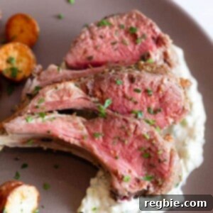 An overhead shot of a brown platter topped with three lamb chops on top of Whole30 tzatziki sauce and Instant pot Crispy potatoes.