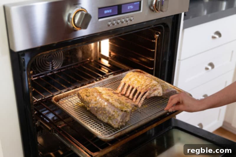 Two Whole30 lamb racks on a wire rack in a rimmed baking sheet are gently placed into a preheated oven for slow roasting.