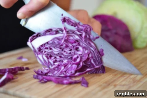 Umami-Rich Red Cabbage Sauté 2 Someone thinly slicing red cabbage on a cutting board for sautéed red cabbage with onions, garlic, and anchovy.