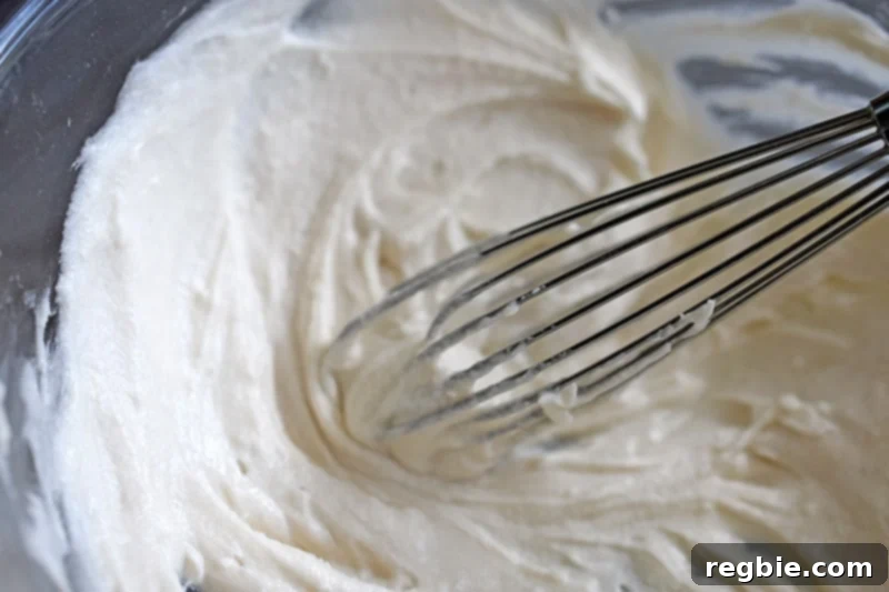 An overhead shot of the smoothly mixed paleo icing, made with coconut milk and powdered sweetener, ready to be drizzled over the warm cinnamon rolls.