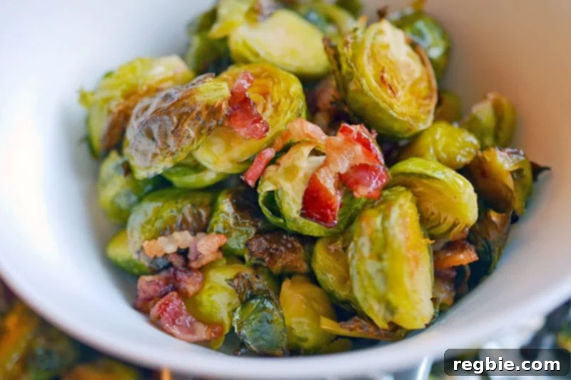 A white bowl filled with perfectly roasted Brussels Sprouts and crispy Bacon bits, ready for serving.