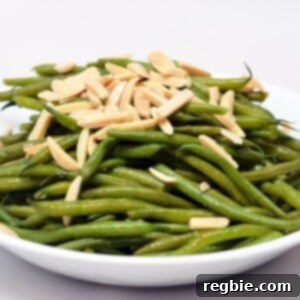 A plate of microwaved green beans in a white bowl topped with slivered almonds.