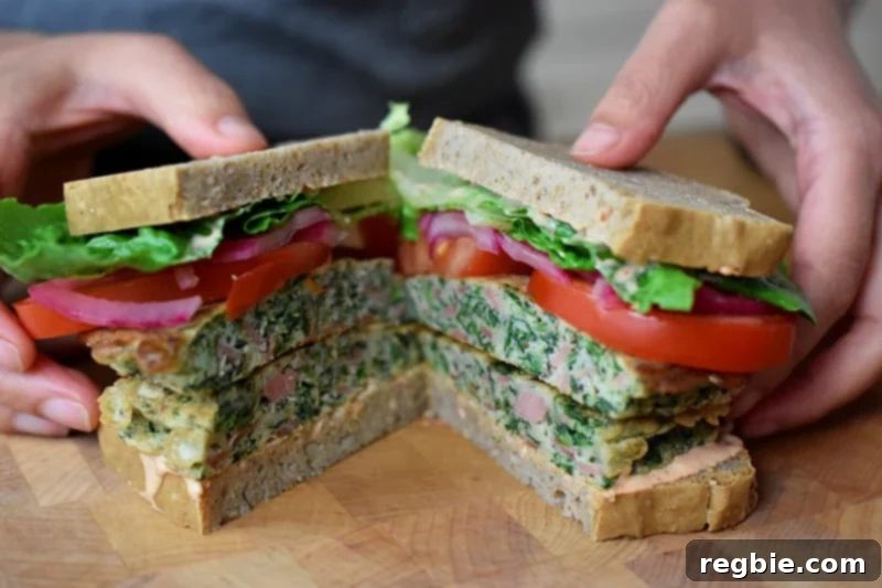 Someone holding two halves of a St. Paul sandwich with gluten-free and paleo-friendly ingredients, displaying its appealing cross-section.