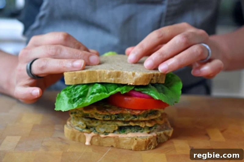 Two hands topping a paleo and gluten free St. Paul sandwich with a slice of grain-free bread, completing the assembly.