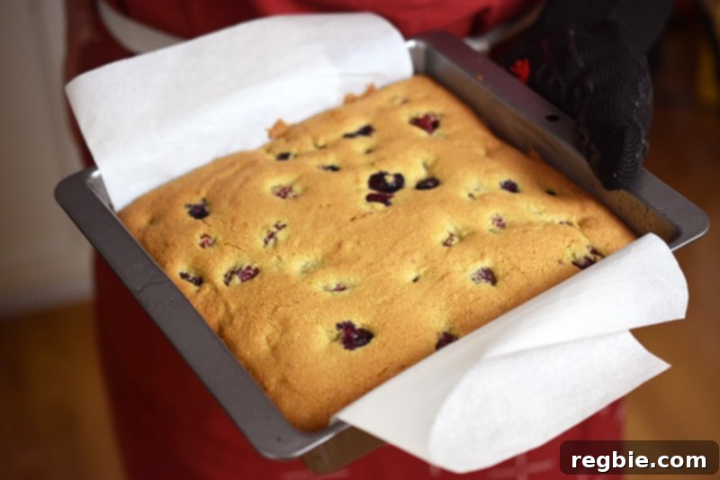 A golden brown berry snack cake is being removed out of the oven.
