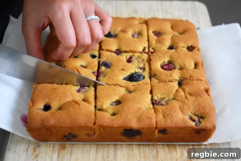 Someone cutting a paleo and gluten-free berry snack cake into nine evenly sized pieces.