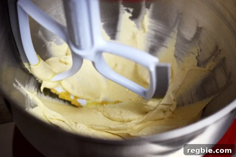 The creamed ghee and maple sugar is now a pale yellow color in the inside of a bowl of a stand mixer.