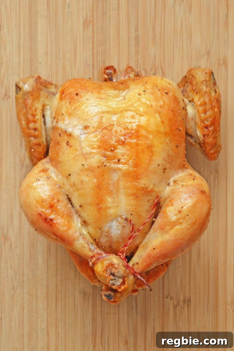 An overhead shot of a perfectly cooked, golden-brown Weeknight Roast Chicken, ideal for paleo and Whole30 diets, resting on a wooden cutting board with succulent browned skin.