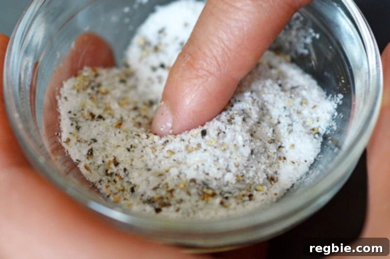 A close-up of a small white ramekin filled with a perfectly blended mixture of salt and pepper, ready to season a flavorful Weeknight Roast Chicken.