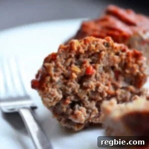 A plate with a paleo meatloaf muffin cut in half, showcasing a hearty and healthy school lunch.
