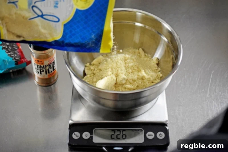 Pouring finely ground almond flour into a large silver bowl placed on a digital kitchen scale, illustrating precise measurement for paleo pumpkin chocolate chip muffins.