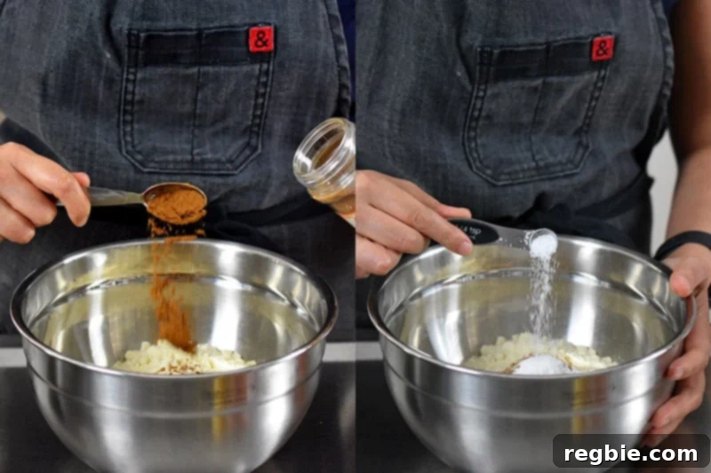 Measuring and combining dry ingredients like almond flour, pumpkin spice, baking soda, cream of tartar, and salt in a silver mixing bowl for gluten-free pumpkin chocolate chip muffins.