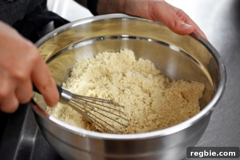 A whisk being used to thoroughly blend the dry ingredients for pumpkin chocolate chip muffins in a bowl.