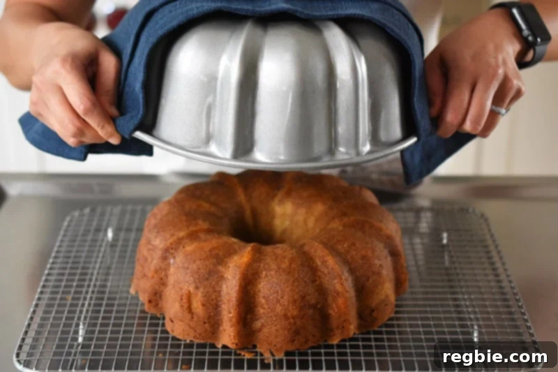 Grain Free Spiced Apple Bundt Cake 17 The process of inverting the apple Bundt Cake onto a wire rack and carefully removing the pan, revealing a perfectly golden-brown cake.