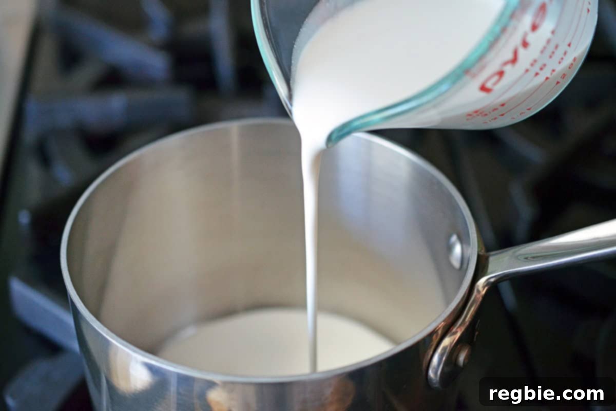 Pouring almond milk from a liquid measuring cup into a small saucepan on the stovetop, though this step is for blender use as per the recipe.
