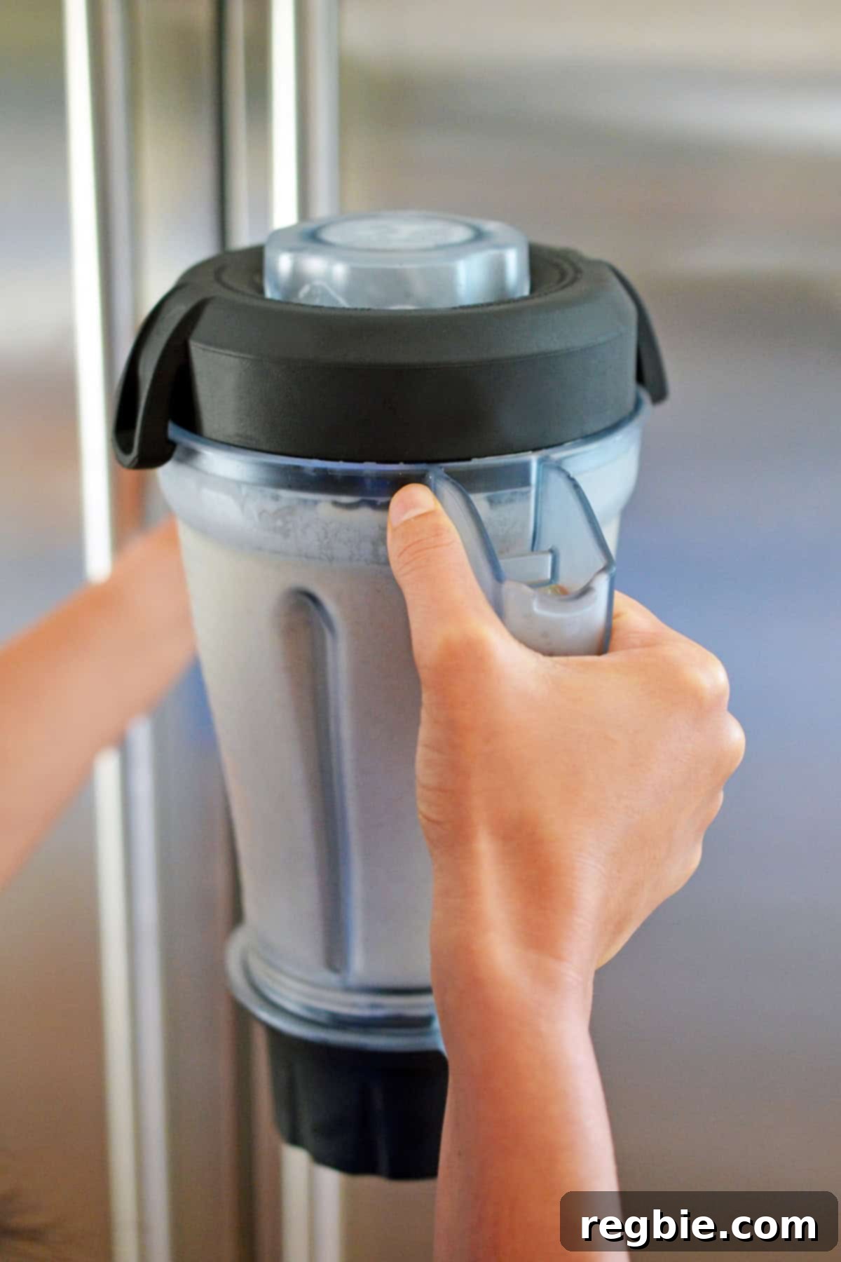 Placing a blender filled with dairy-free vanilla ice cream batter into the refrigerator to chill.
