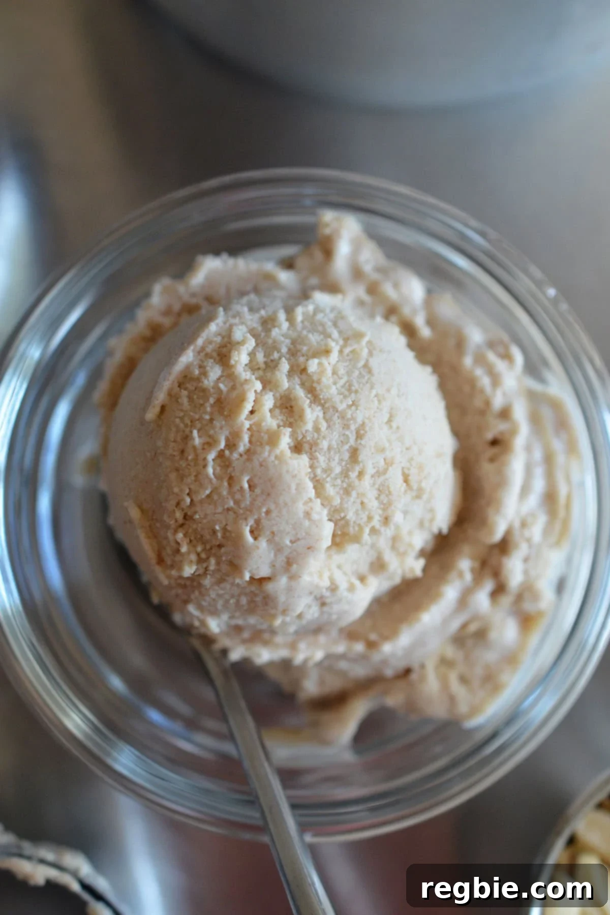 An overhead shot of a generous scoop of dairy-free and paleo vanilla ice cream in a small glass bowl, with a spoon nestled invitingly within.