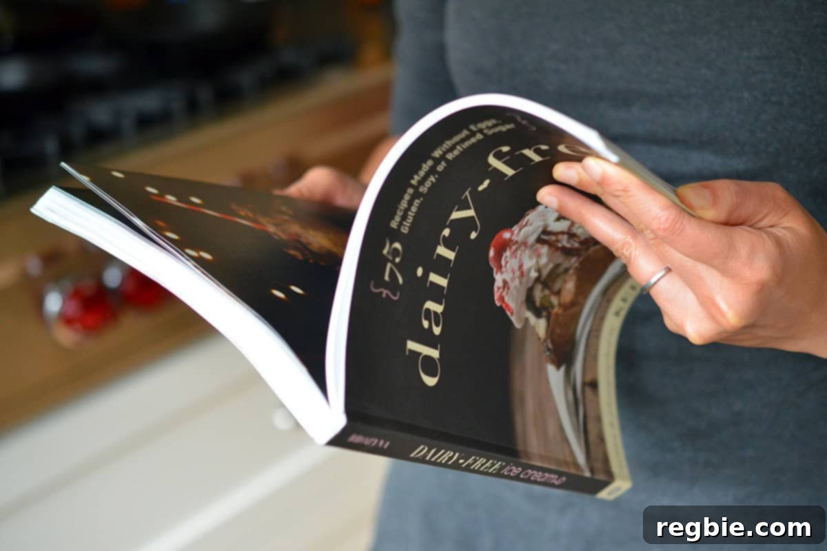 A person holding a paperback copy of the 'Dairy-Free Ice Cream' cookbook, inspiring delicious homemade treats.