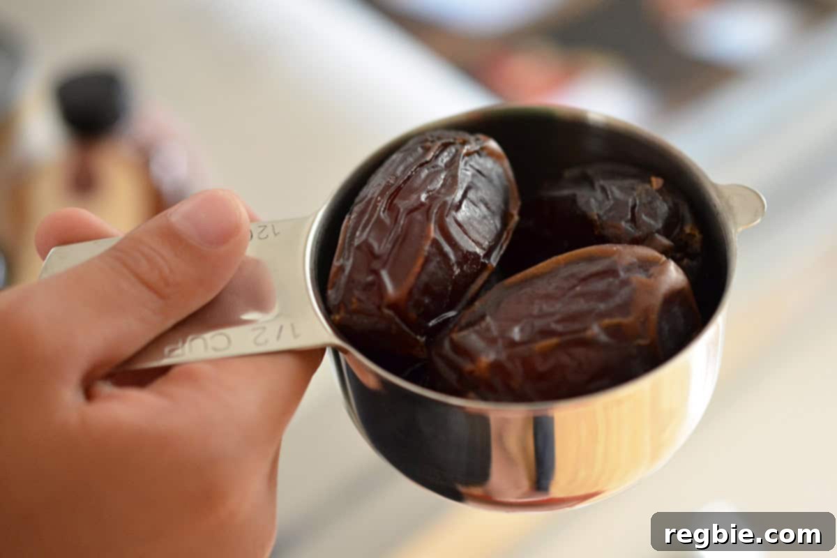 Pitted Medjool dates in a metal measuring cup, ready for blending.