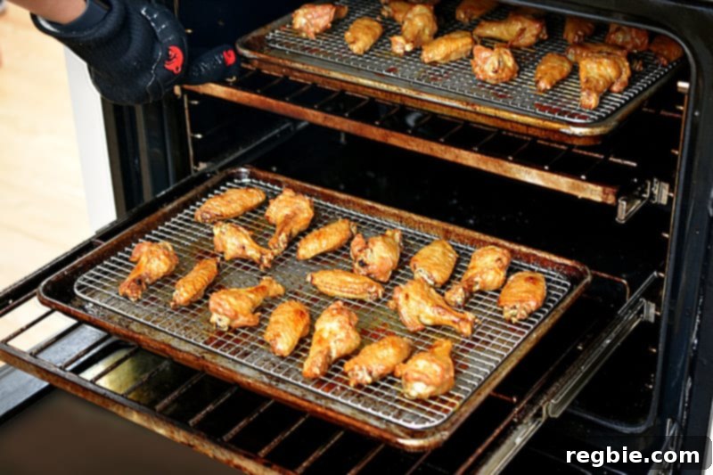 An open oven proudly showcasing perfectly golden brown and crispy chicken wings on a baking sheet, indicating they are fully cooked and ready to be removed for saucing.