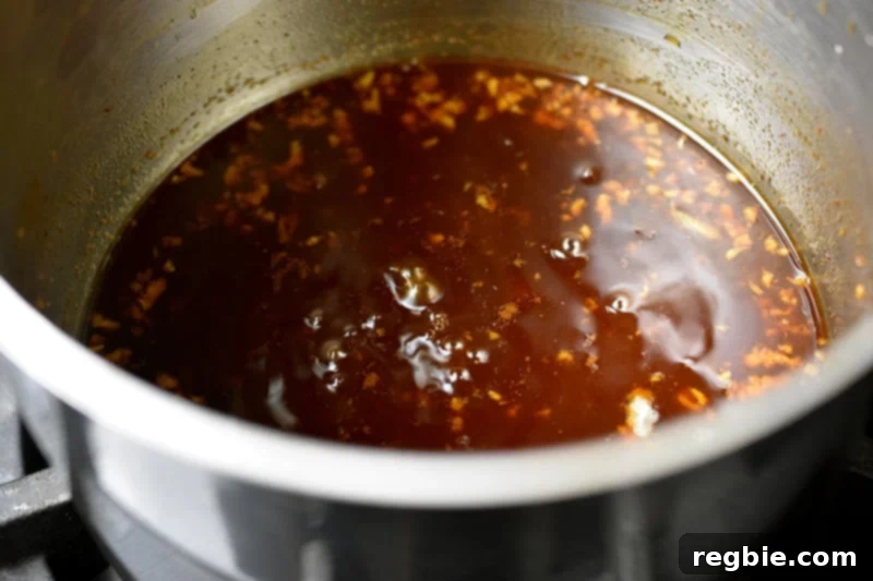 An overhead shot of a small saucepan where the Asian sauce is gently simmering, thickening and reducing as it cooks, reaching a perfect sticky consistency.