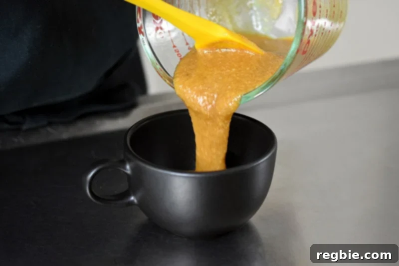 Quick Paleo Gluten-Free Pumpkin Mug Cake 6 Pouring pumpkin mug cake into a black coffee mug.