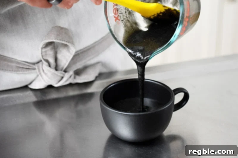 Paleo Black Sesame Mug Cake Indulgence 7 Pouring the black sesame mug cake batter into an elegant black tea cup, ready for microwaving.