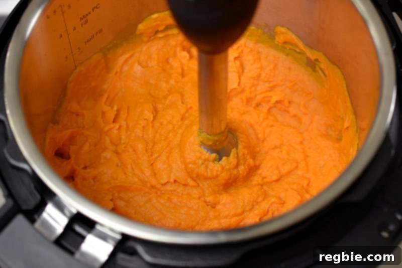 An overhead shot of an immersion blender blending together instant pot mashed sweet potatoes