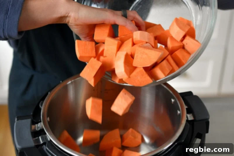 Someone dumping sweet potato cubes into an open Instant Pot