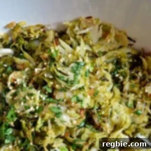 Warm Brussels Sprouts Slaw with Asian Citrus Dressing by Michelle Tam https://nomnompaleo.com. A vibrant warm salad, glistening with dressing, ready to serve.