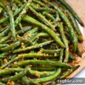A closeup shot of paleo, Whole30, and gluten free Chinese garlic green beans in a skillet, perfectly blistered and seasoned.