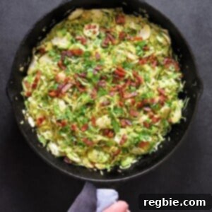 An overhead shot of shaved Brussels sprouts with bacon in a large cast iron skillet, perfectly sautéed.