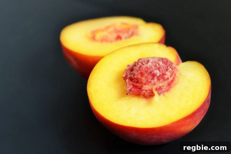 A peach sliced in half sitting on a counter.