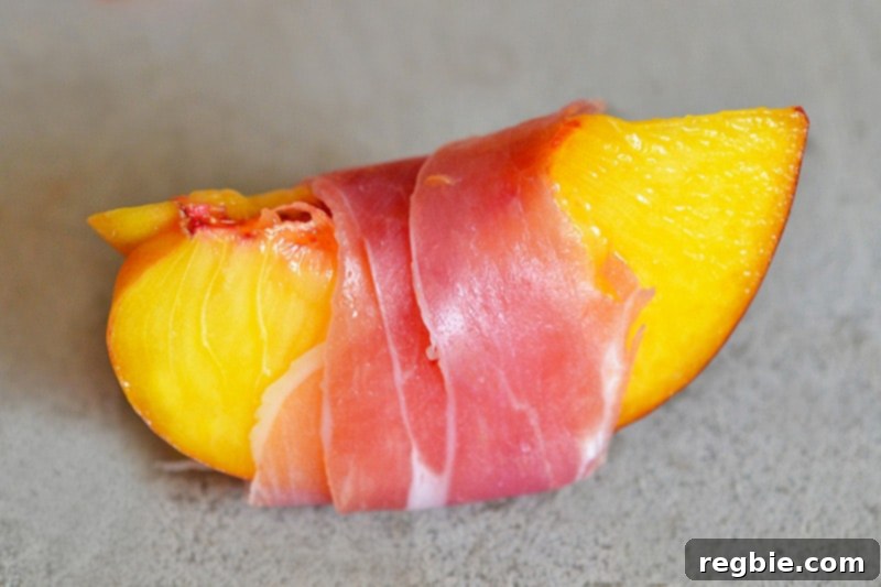 A quartered peach wrapped with a thin slice of prosciutto.