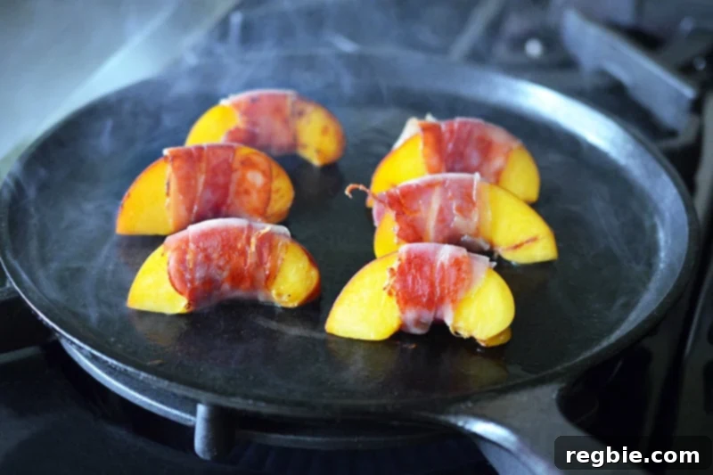 Prosciutto wrapped peaches searing on a cast iron skillet.
