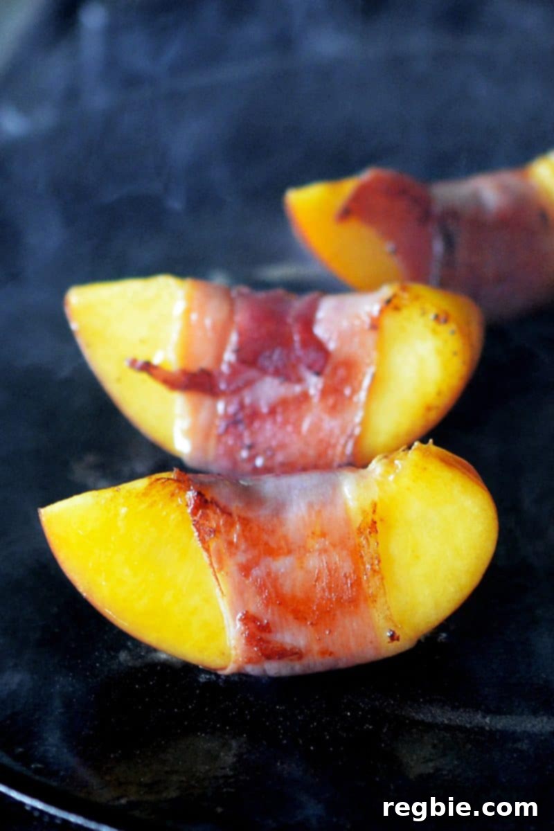 A close up of prosciutto-wrapped peached searing on a cast iron skillet.