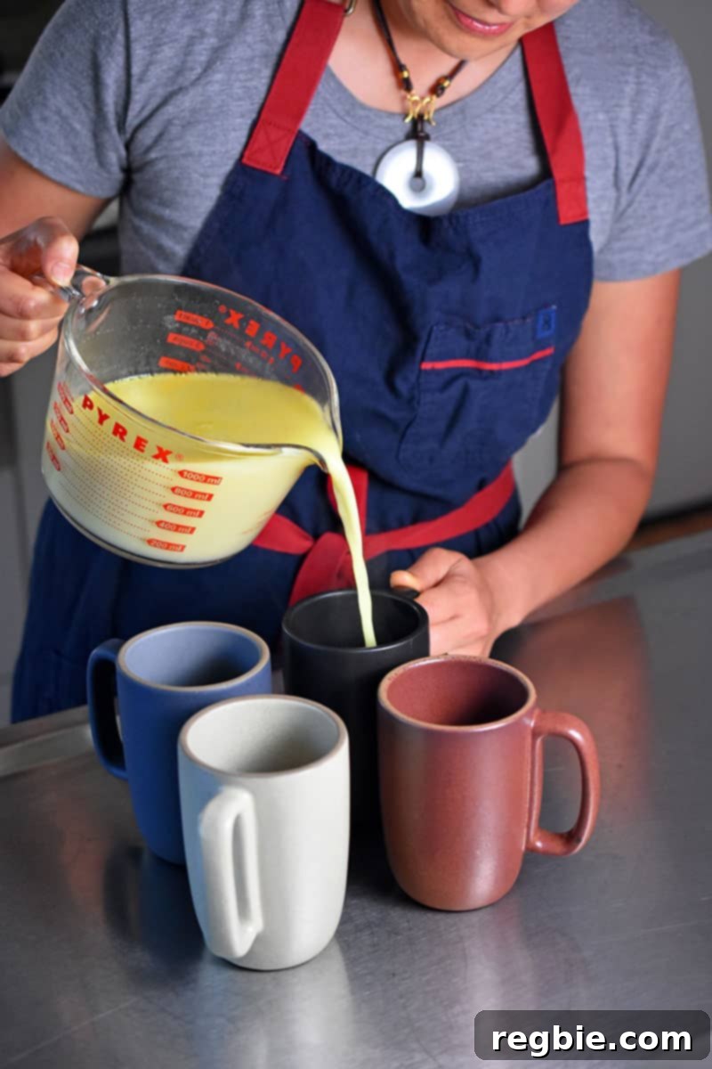 Paleo Dairy-Free Golden Turmeric Elixir 7 Someone pouring the Golden Milk into four coffee mugs.