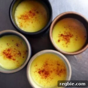 An overhead shot of four mugs filled with Golden Milk topped with ground cinnamon
