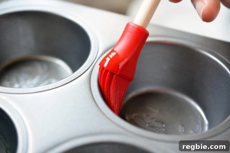 Brushing grease in the muffin tins.