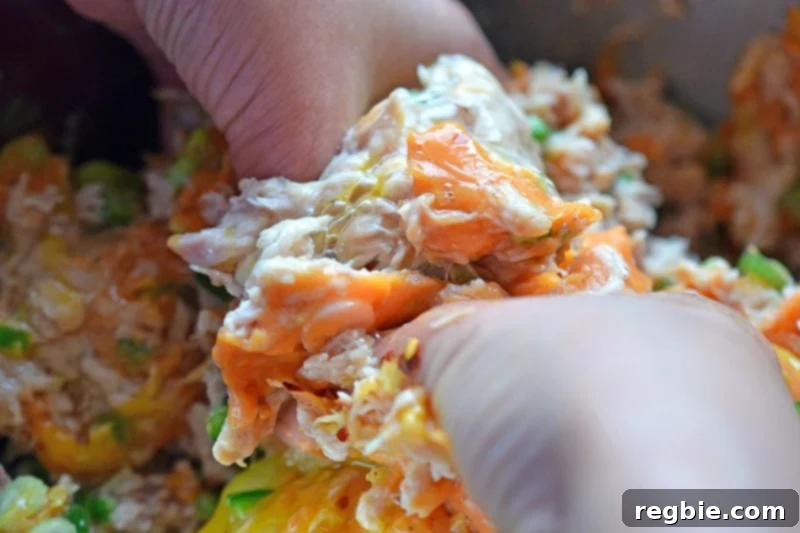 Someone mixing together the spicy tuna cake mixture with their hands.