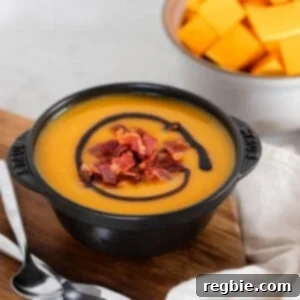 A black bowl filled with Instant Pot Butternut Squash Soup on a wooden cutting board.