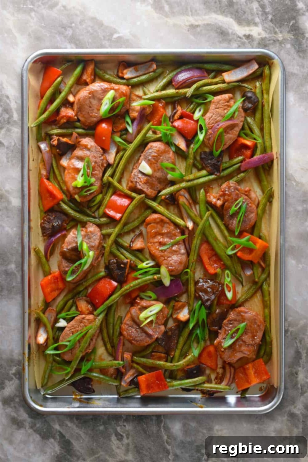 Overhead shot of a vibrant sheet pan sweet and spicy pork meal, showcasing perfectly cooked pork and vegetables.