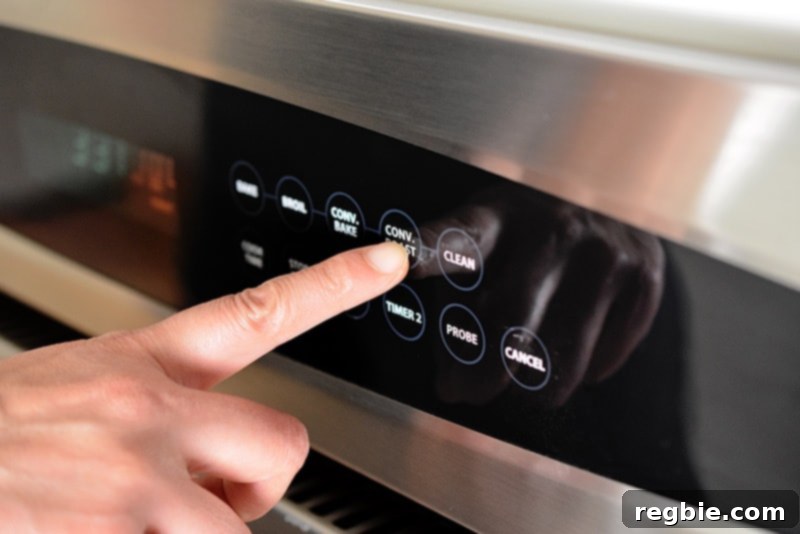 A finger pressing the convection roast button on an oven display, indicating the oven is being set for optimal crispy cooking.
