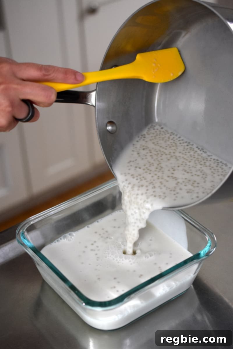 Tropical Mango Coconut Tapioca 15 A shot of someone transferring coconut milk tapioca pudding from a saucepan into a glass square container.