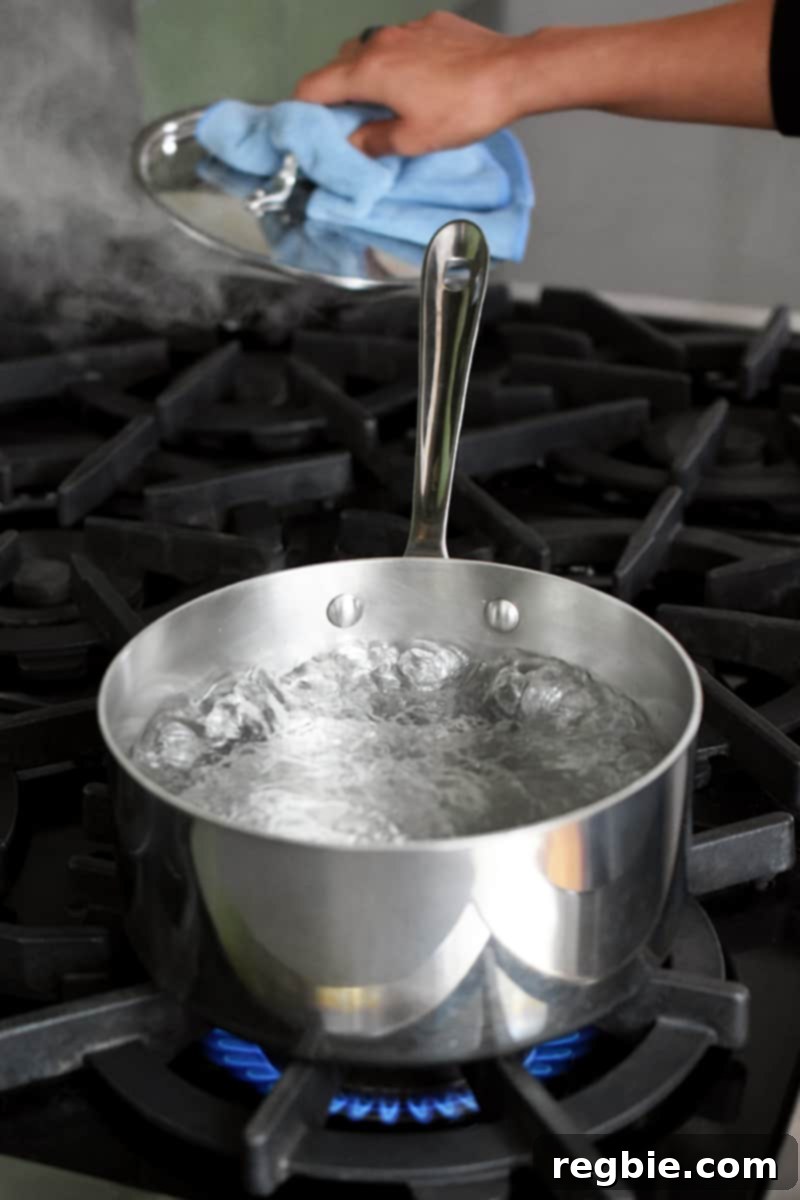 Tropical Mango Coconut Tapioca 6 A stainless steel saucepan is filled with boiling water on a stovetop.