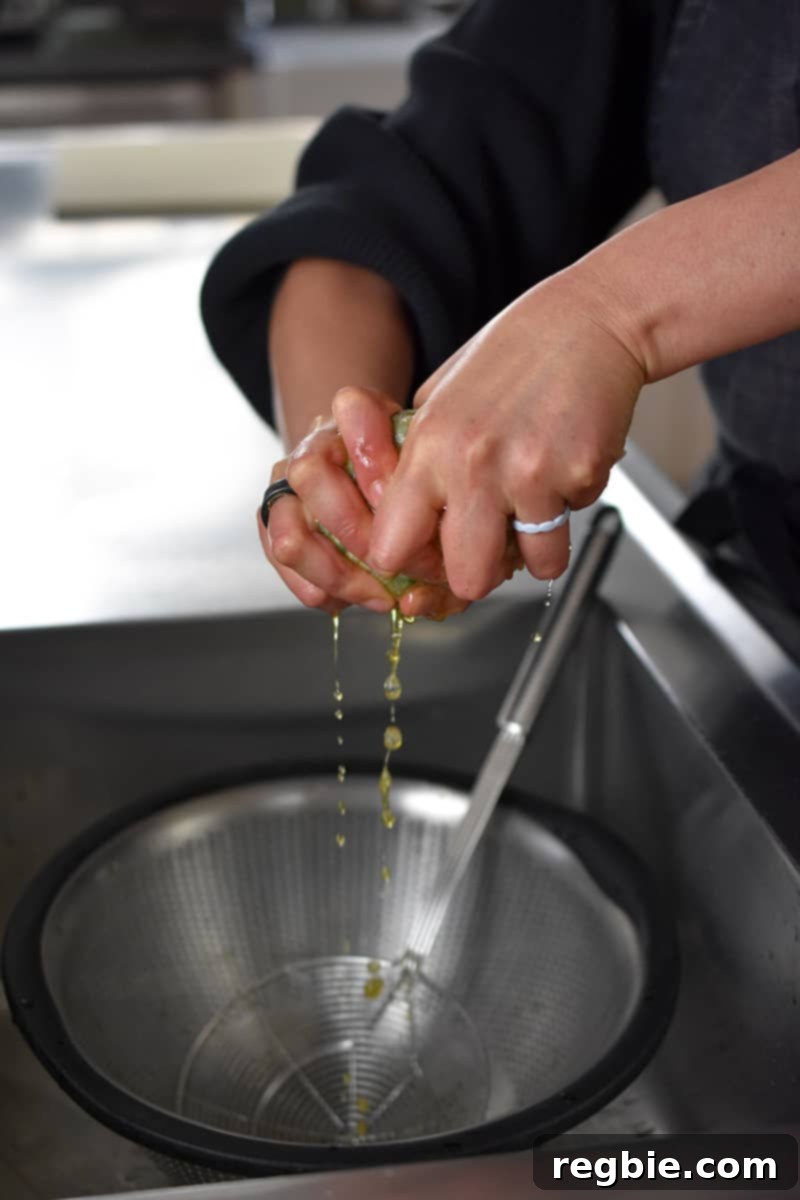 Garden Colcannon 11 Two hands are wringing the liquid out of the cooked kale wrapped in a piece of cheesecloth.