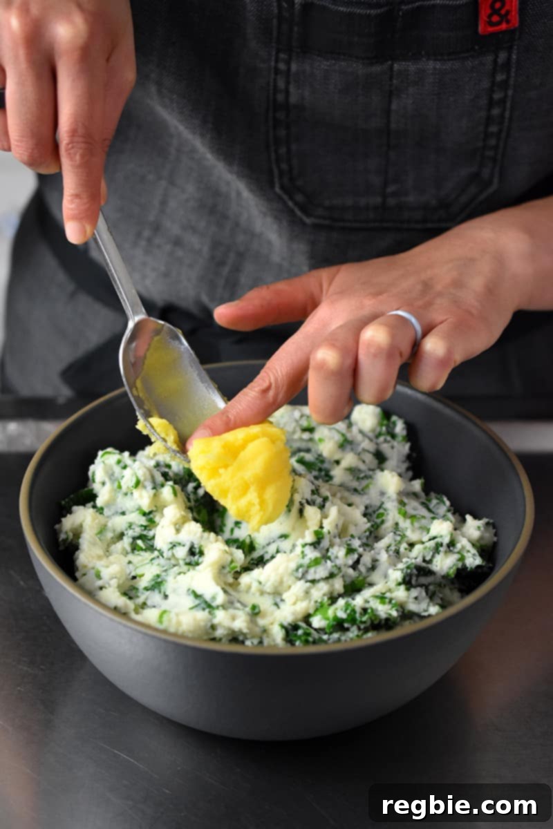 Garden Colcannon 18 A hand is pushing a dollop of ghee into a bowl of cauliflower colcannon.