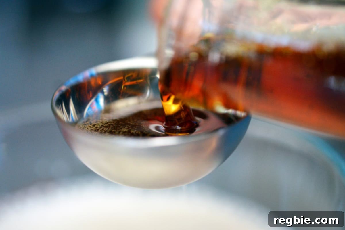 Pouring maple syrup into a measuring spoon.