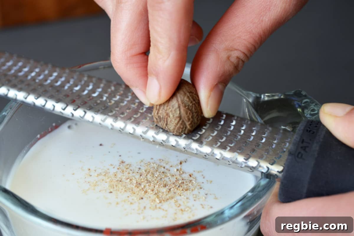 Grating nutmeg with a microplane rasp grater into a measuring cup filled with sweetened almond milk.